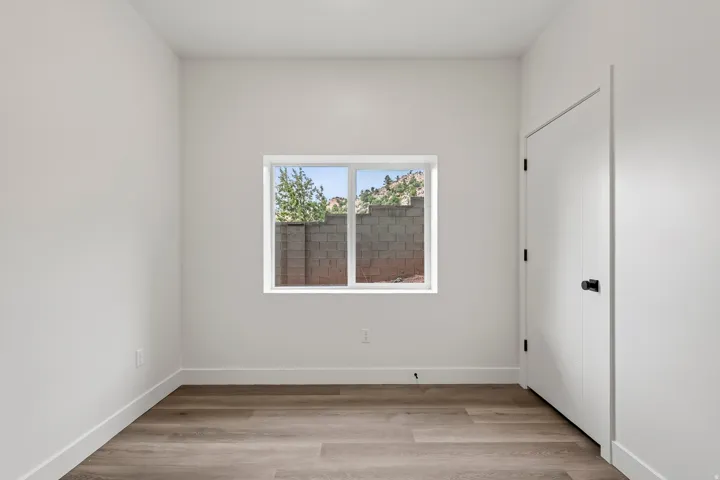 Wood-finish flooring, white walls, and a window with a white frame