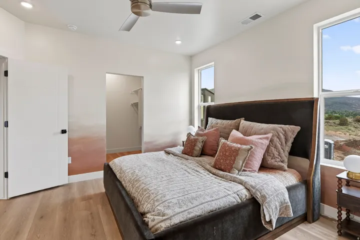Recessed lighting, wood-finish flooring, ceiling fan, large windows, and an open closet space with shelving