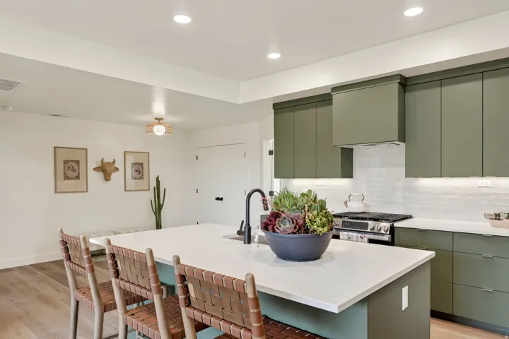 Kitchen featuring green cabinetry, white tile backsplash, a center island with a white countertop, and recessed lighting