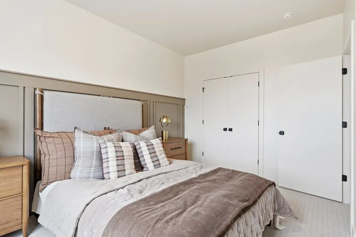 Wall paneling with integrated upholstered headboard, dual white panel doors, and wood-finish flooring