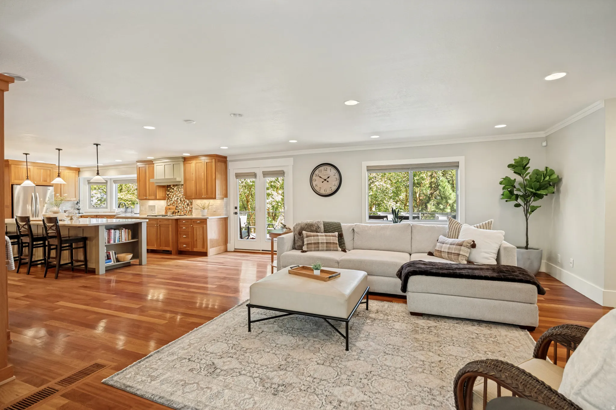 Expansive main living area featuring wood-finish flooring, recessed lighting, and a kitchen with wood cabinetry and an island