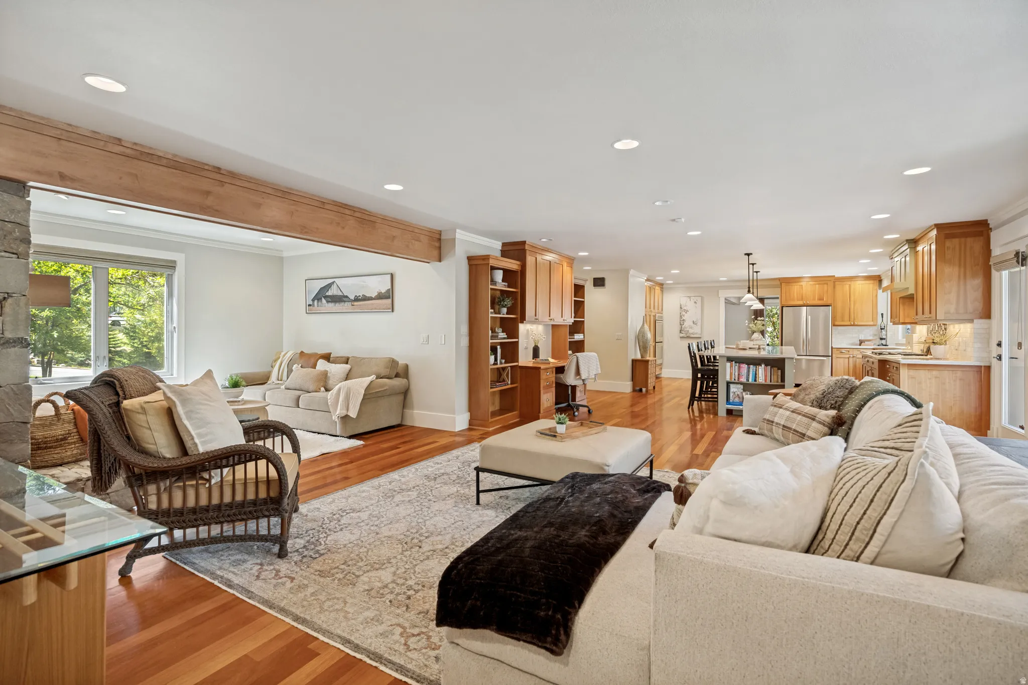 Open-concept living space featuring wood-finish flooring, exposed ceiling beams, recessed lighting, and built-in shelving