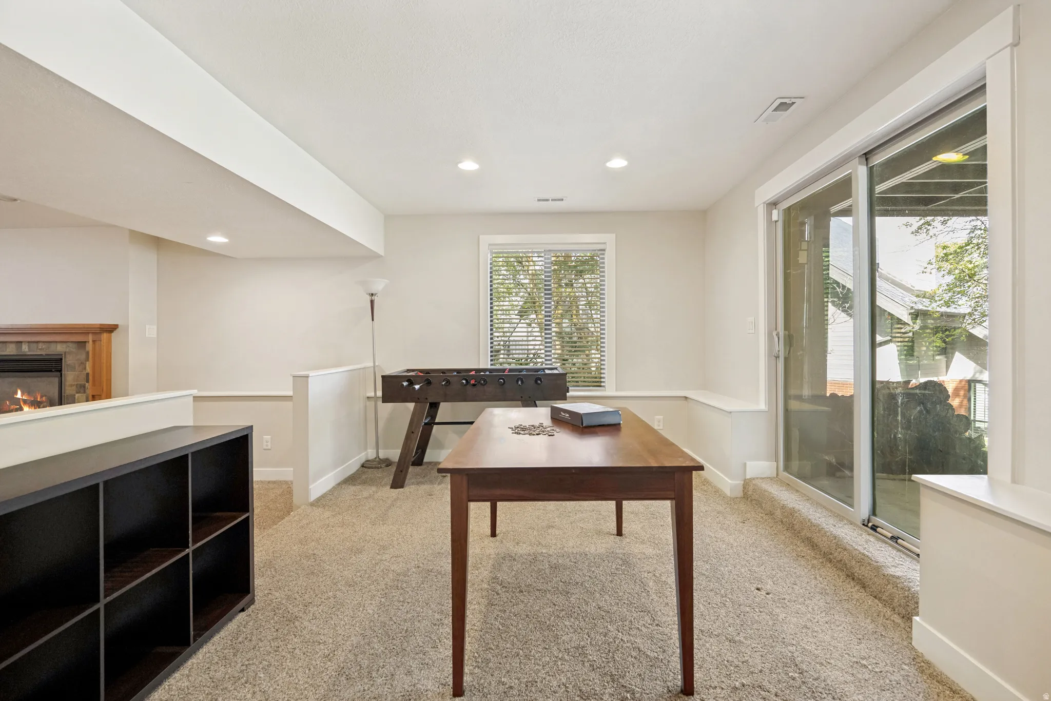 Carpeted recreation room with recessed lighting and a fireplace featuring a stone surround and wood mantel