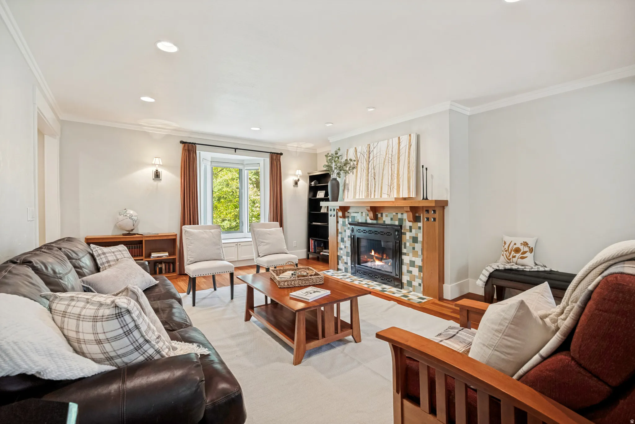 Recessed lighting, crown molding, wood-finish flooring, bay window, and a fireplace with tile surround
