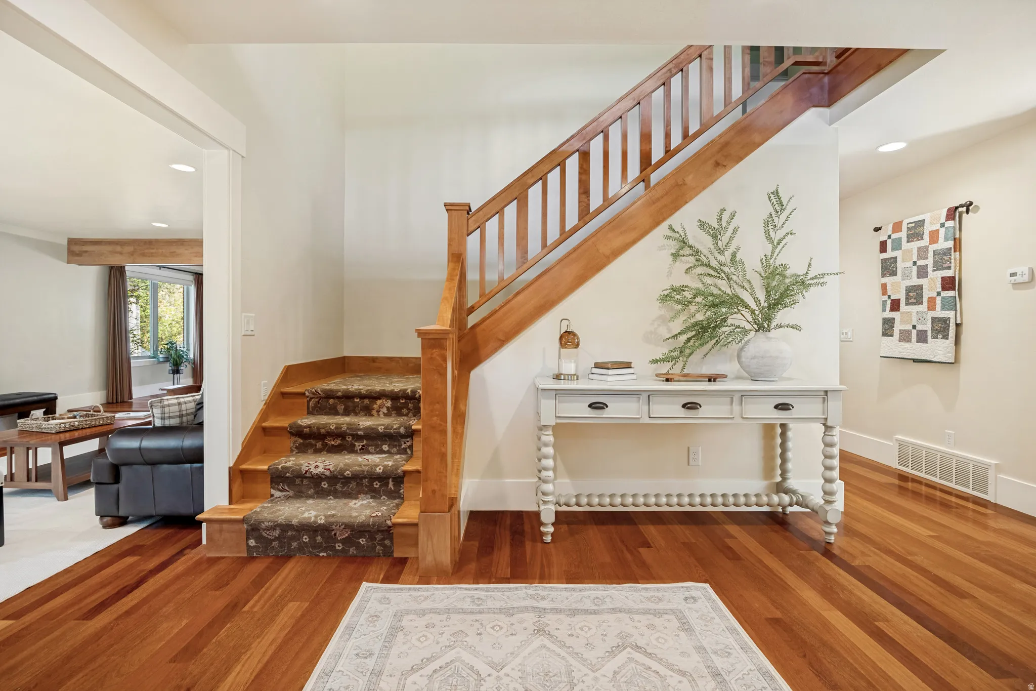 Hardwood flooring, wood staircase with carpeted treads, built-in recessed lighting