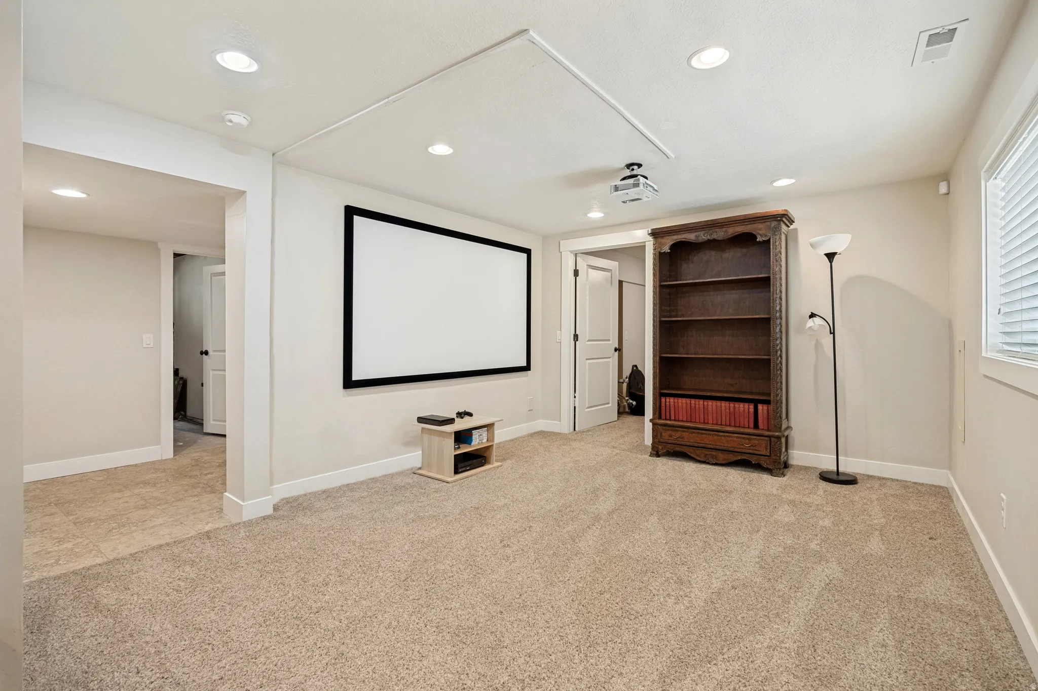 Recessed lighting, soft neutral carpeting, a built-in projection screen, and white trim