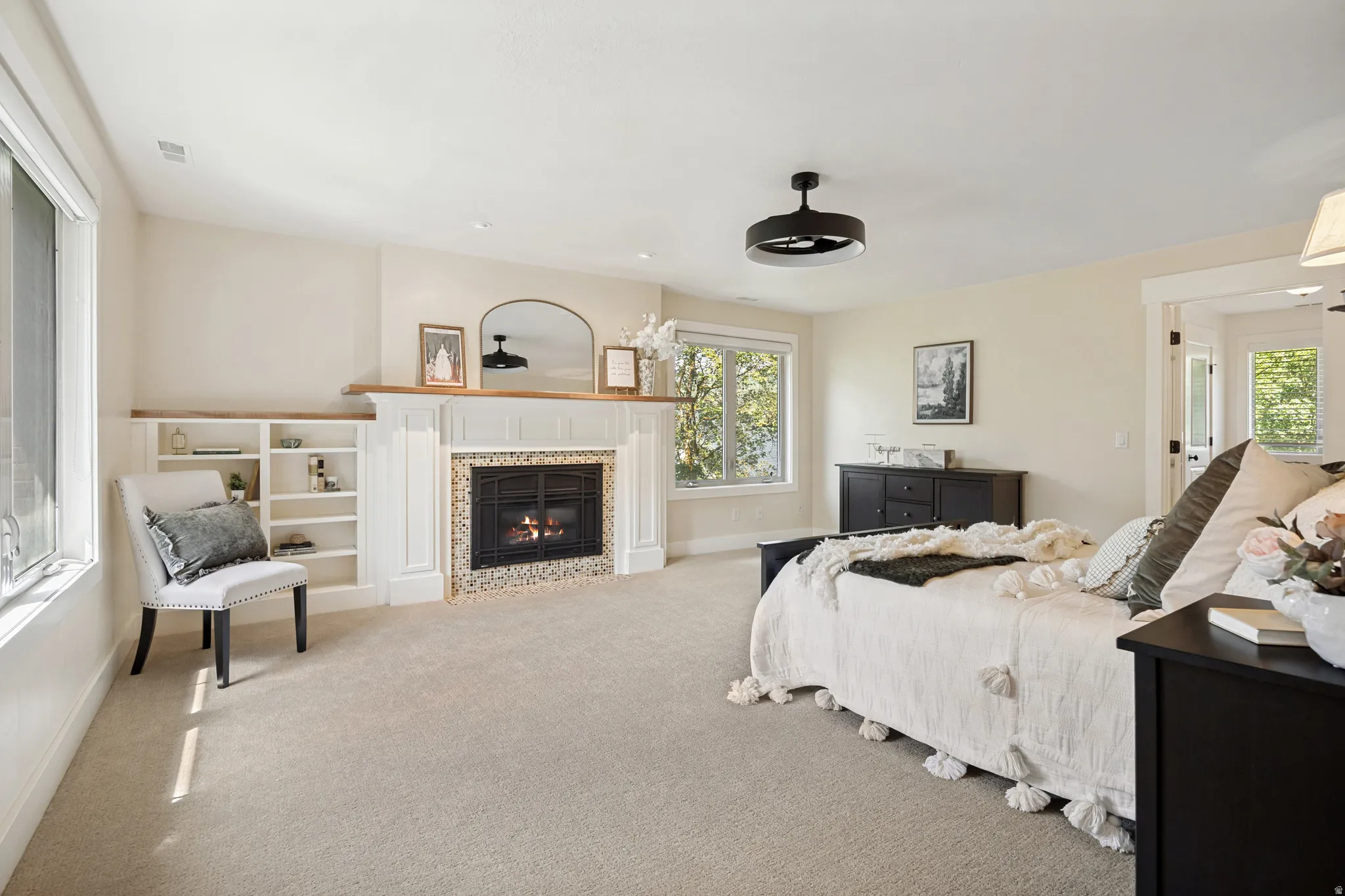 Built-in shelving, fireplace with tiled surround, wood mantel, and broad windows
