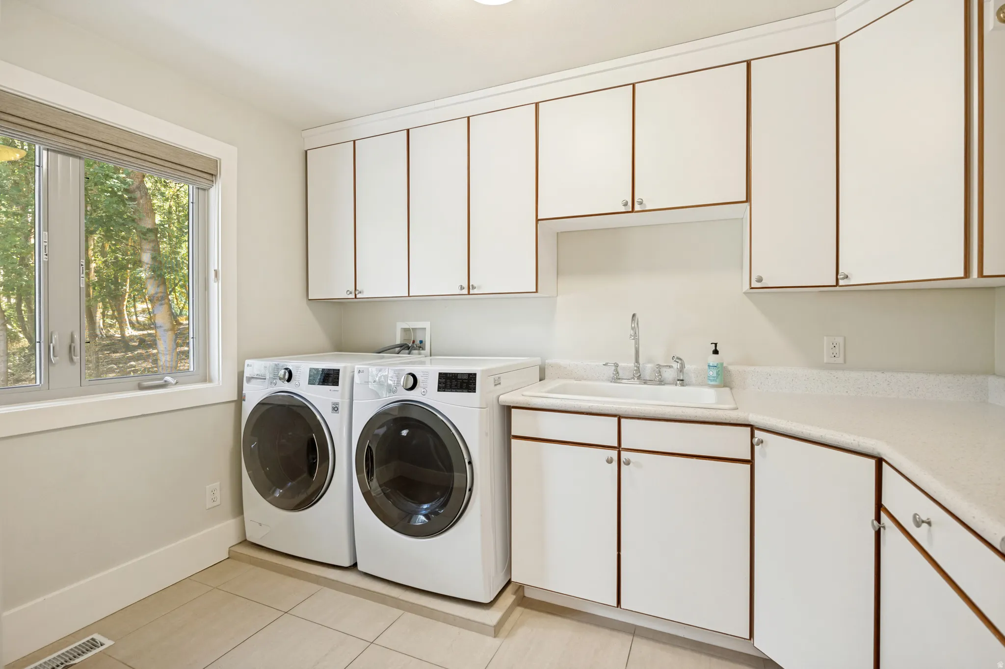 White cabinetry with contrasting trim, integrated sink with chrome faucet, light-colored countertops, and tiled flooring