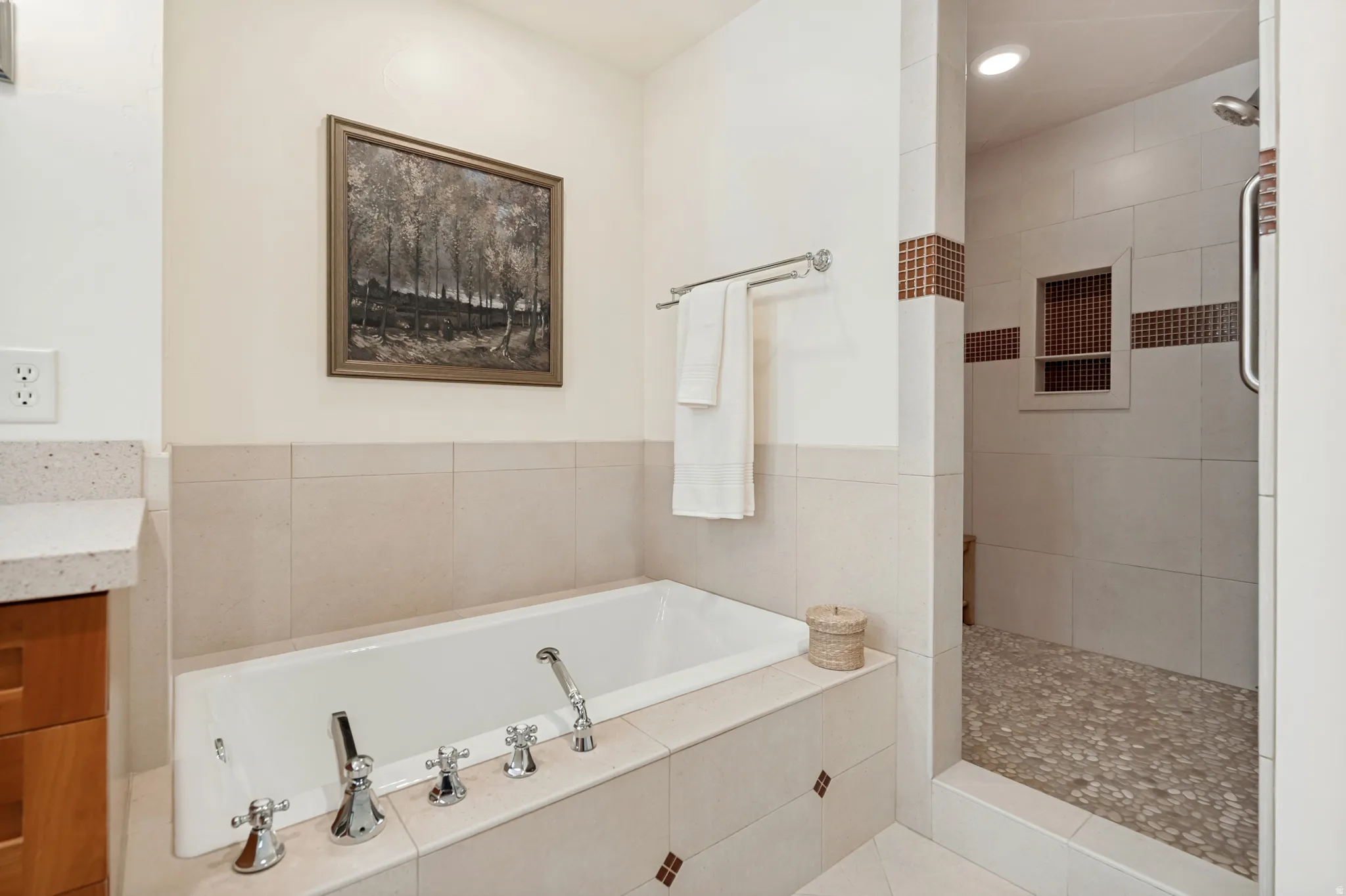 Built-in bathtub, walk-in shower with mosaic tile accents, and a stone pebble shower floor