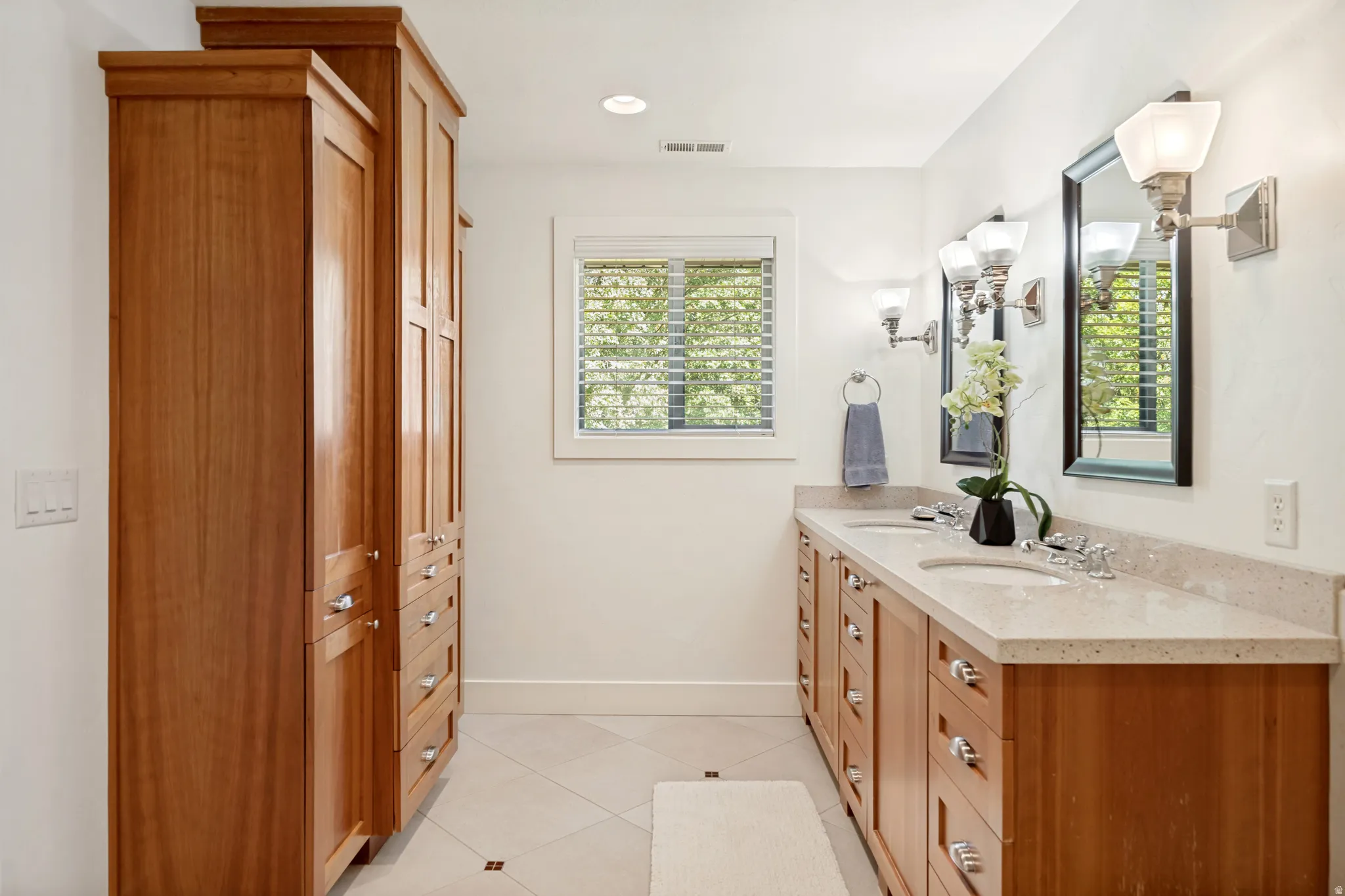 Dual vanity with integrated sinks, light-toned countertop, and wood-finish cabinetry