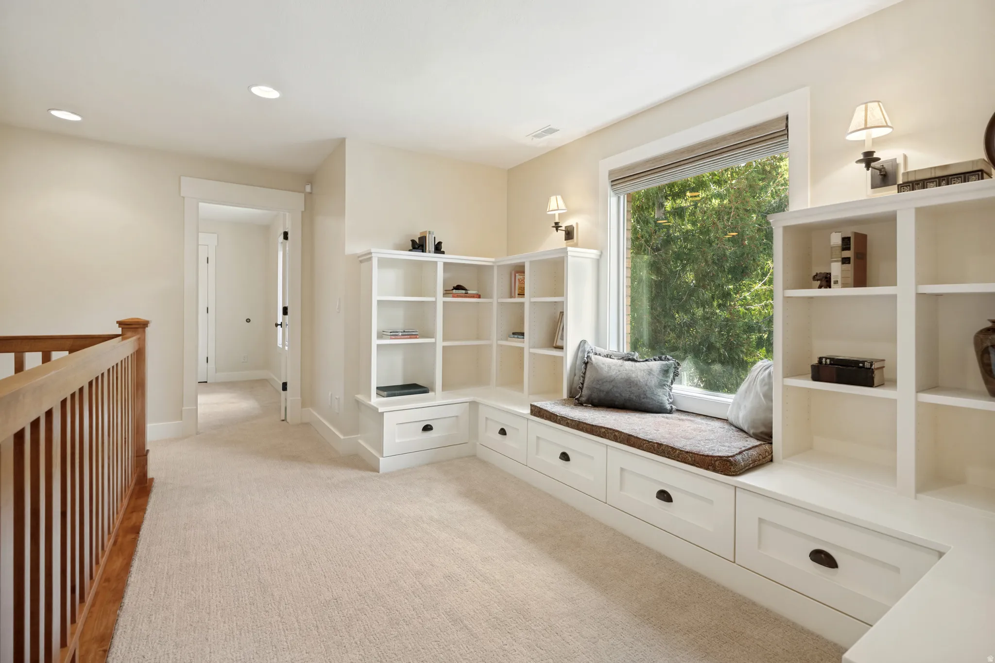 Built-in window seat with storage drawers, integrated shelving, and wall sconces