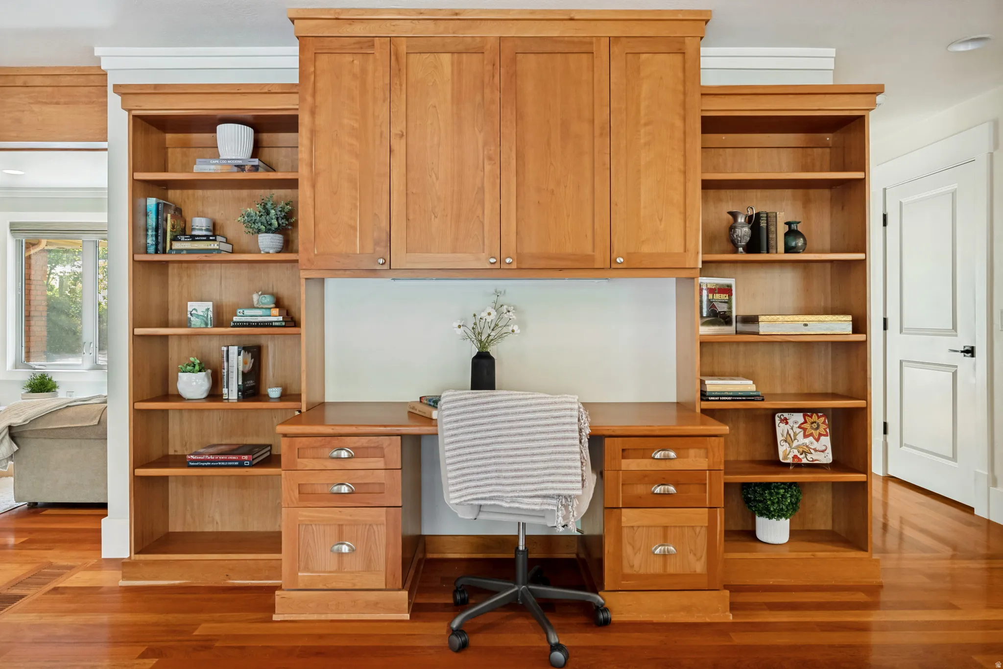 Built-in wood-finish desk with integrated cabinetry, shelving, and drawer storage