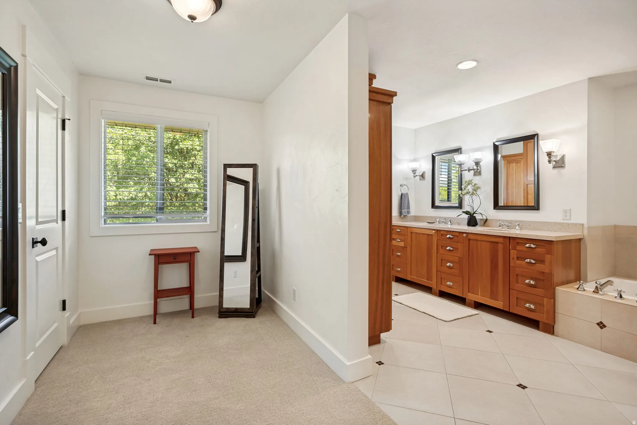 Dual vanity with wood cabinetry and undermount sinks, integrated soaking tub, tiled flooring with accent inlays