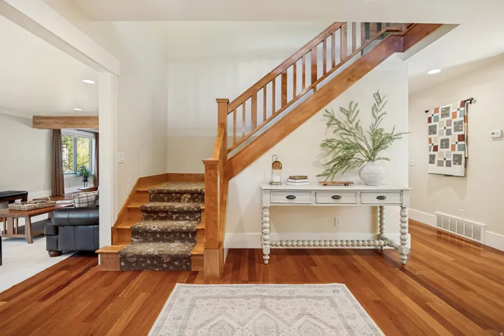 Hardwood flooring, wood staircase with carpeted treads, built-in recessed lighting