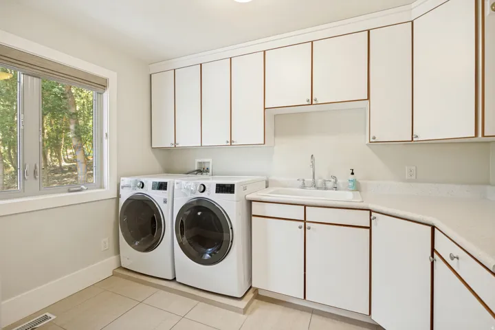 White cabinetry with contrasting trim, integrated sink with chrome faucet, light-colored countertops, and tiled flooring