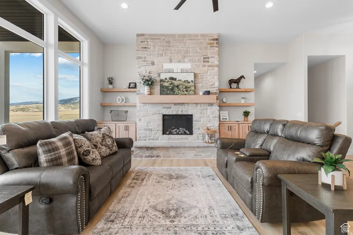 Stone-faced fireplace with a wood mantel, built-in shelving, and light wood-finish flooring