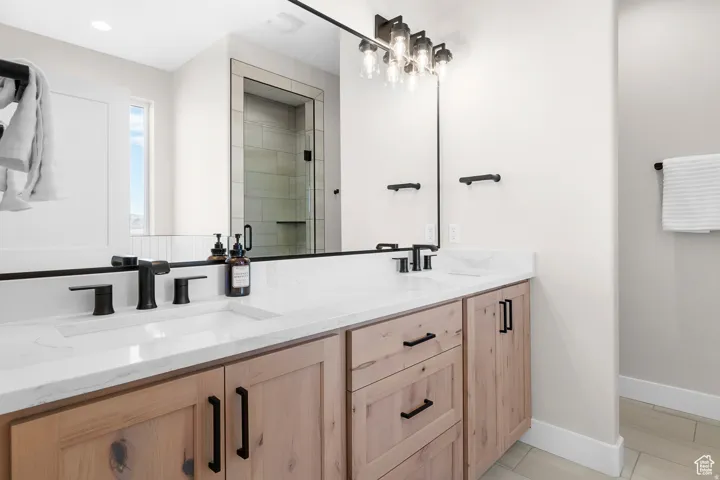 Dual vanity with integrated sinks, white countertop, and natural wood-finish cabinetry with black hardware