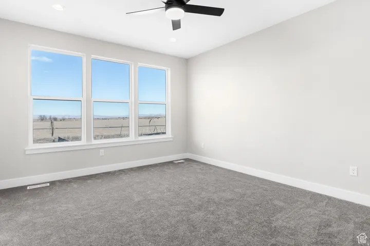 Room featuring three large windows, a ceiling fan with integrated lighting, recessed lighting, and grey carpeting