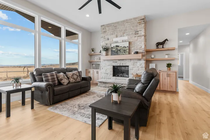 Living area featuring floor-to-ceiling windows, a stacked stone fireplace, a natural wood mantel, built-in cabinetry, and wood-finish flooring