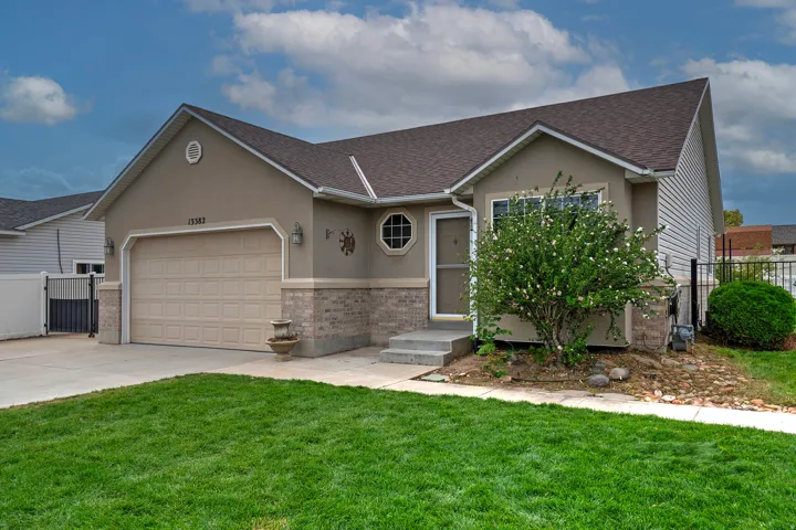Stucco exterior with brick detailing, asphalt shingle roof, two-car garage, and front landscaping