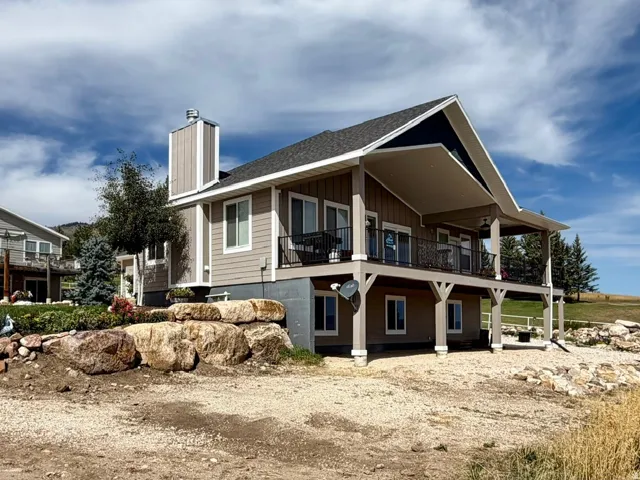 Two-story residence featuring a covered upper-level deck, a covered lower-level patio, and a prominent chimney