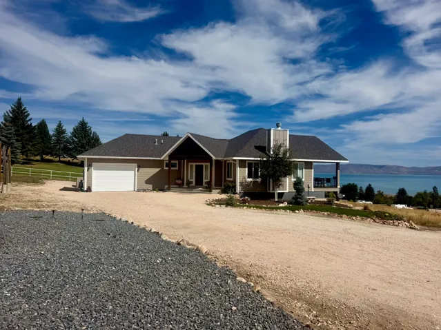 Lakefront residence featuring a two-car garage, covered porch, and expansive water frontage
