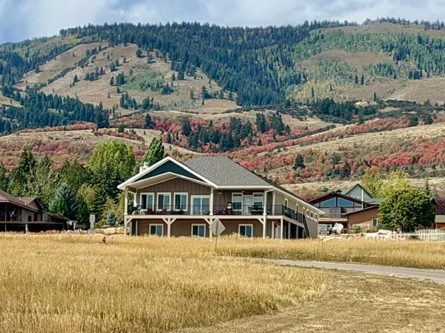 Expansive property featuring a multi-level structure with covered balconies, a pitched roof, and a surrounding natural landscape