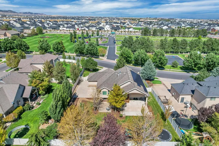 Expansive residential property featuring a tan exterior, mature landscaping, and a large backyard patio