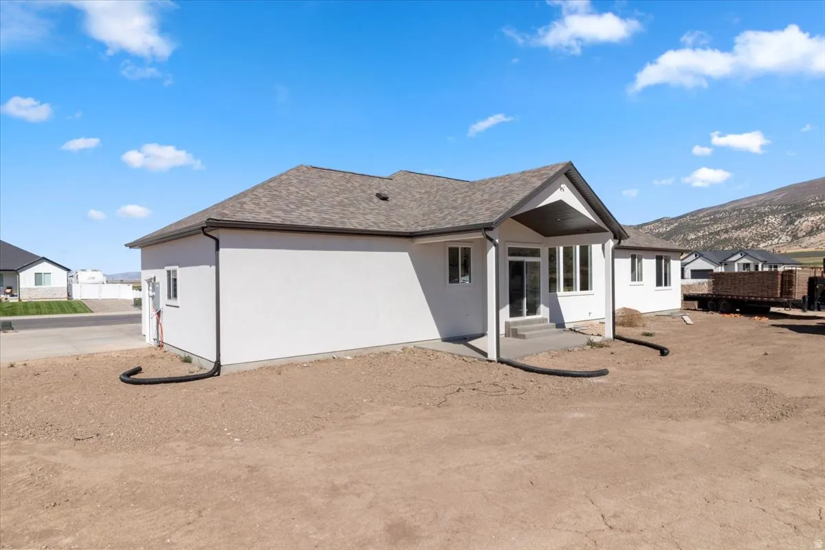 Rear exterior with covered patio, white stucco siding, and multi-paned windows