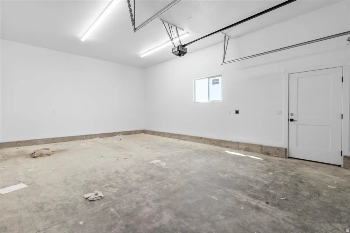 Spacious garage featuring a concrete floor, white painted walls, and overhead fluorescent lighting