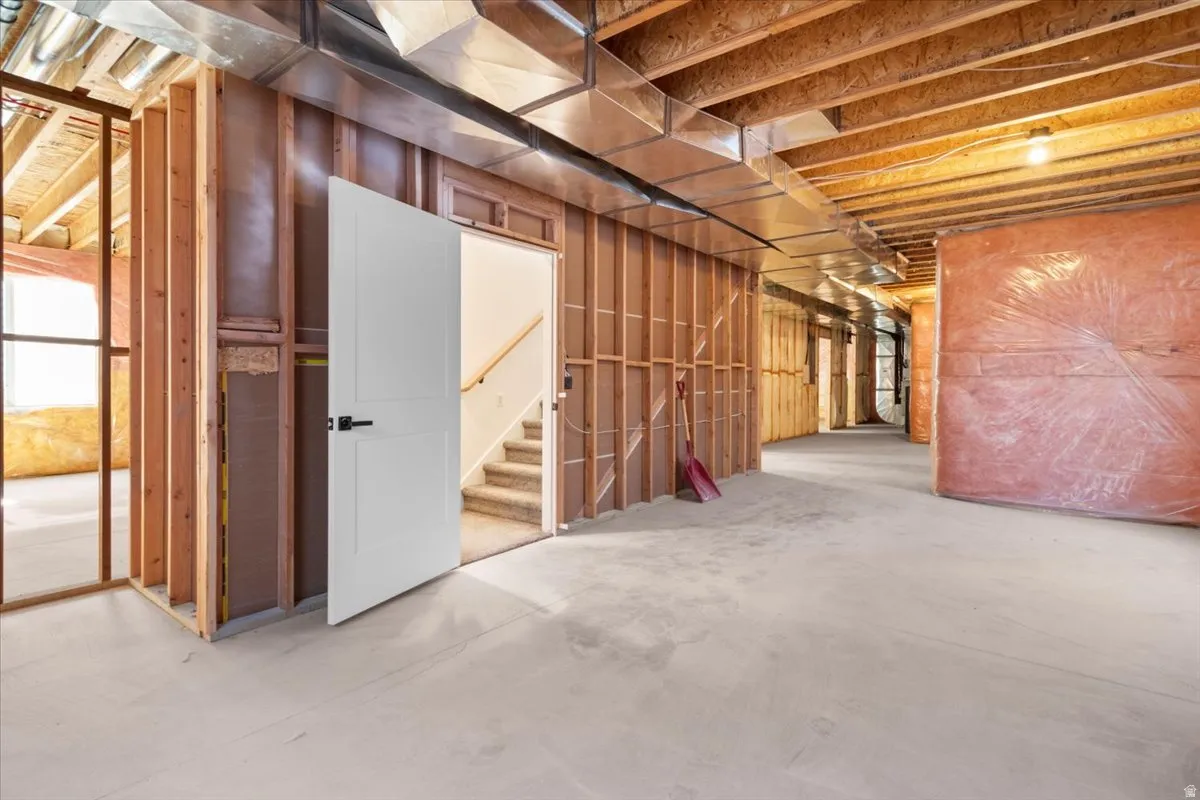 Unfinished basement with exposed wood framing, concrete flooring, and visible ductwork