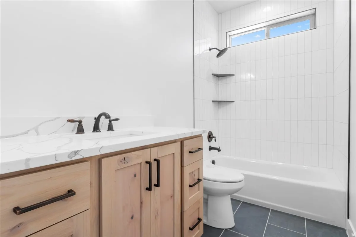 Vanity with a quartz countertop, bronze-finish faucet, and wood-panel cabinetry