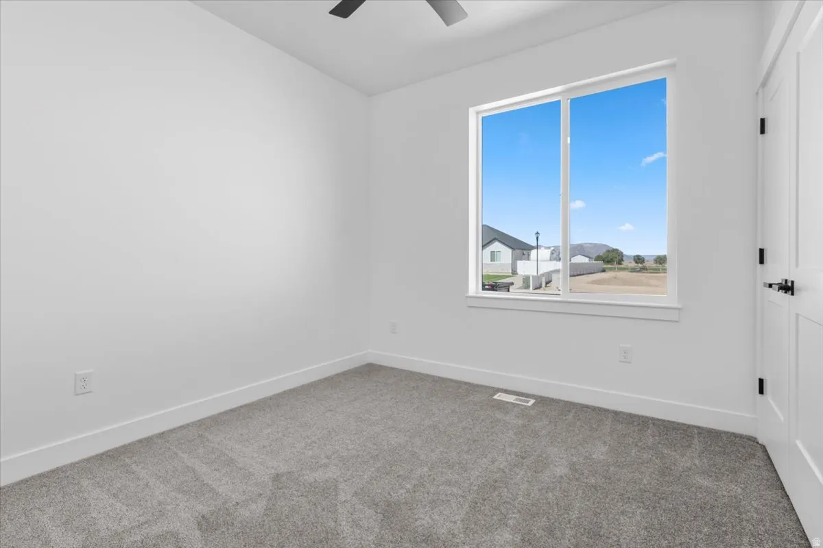 Recessed window, white paneled door with matte black hardware, gray carpet, and white walls