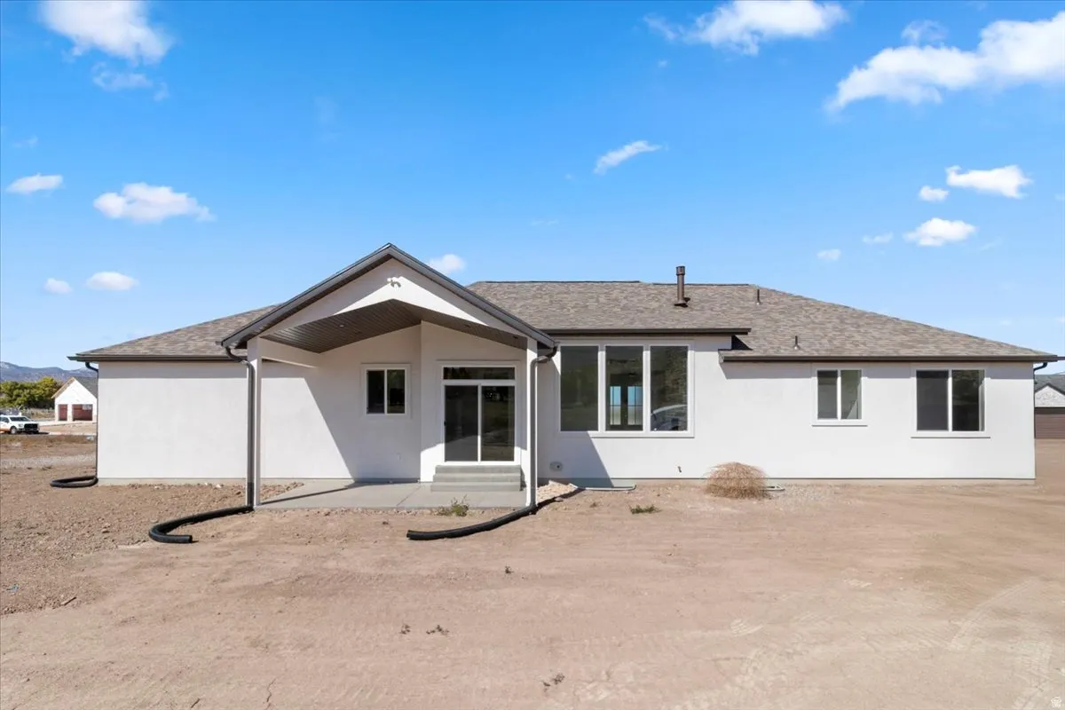 White stucco exterior with a covered patio and concrete pad