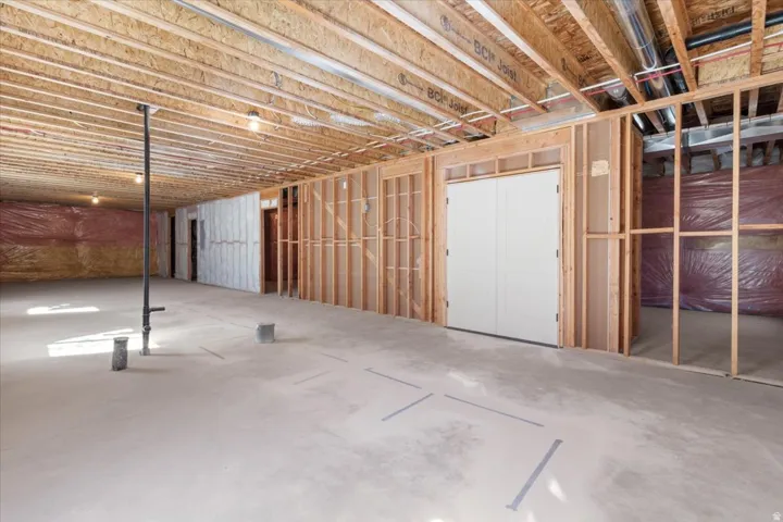 Unfinished basement with concrete flooring, exposed wood framing, and overhead joists