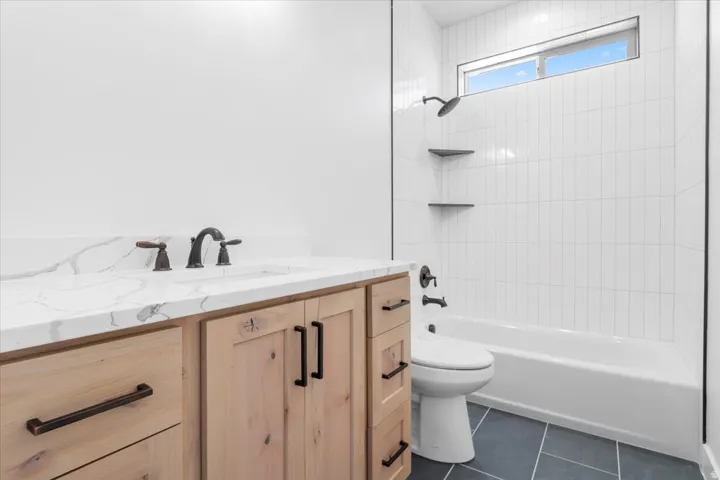 Vanity with a quartz countertop, bronze-finish faucet, and wood-panel cabinetry