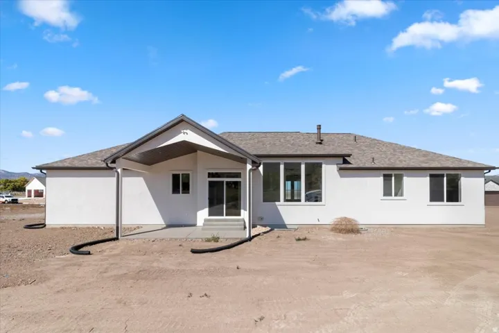 White stucco exterior with a covered patio and concrete pad