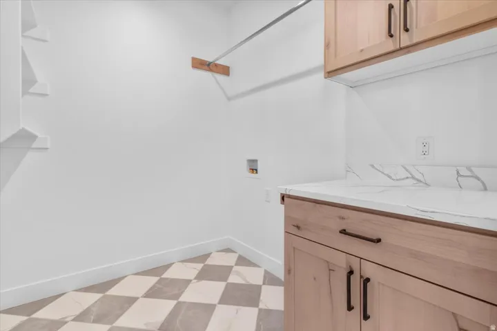 Chequered floor tiles, wood-finish cabinetry, white countertops with veining, and a built-in hanging rod