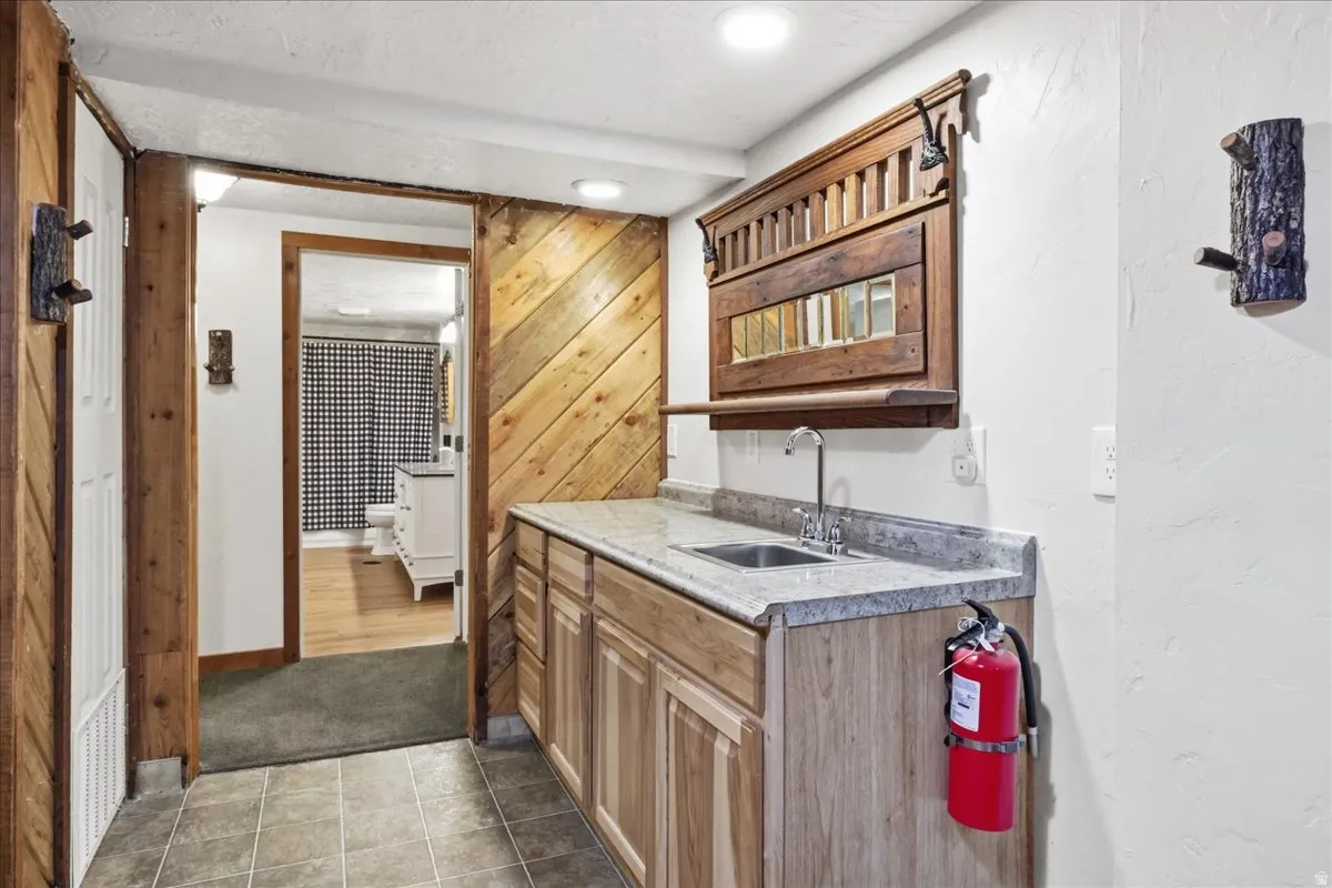 Wet bar featuring a stainless steel sink, chrome faucet, and stone-finish countertop
