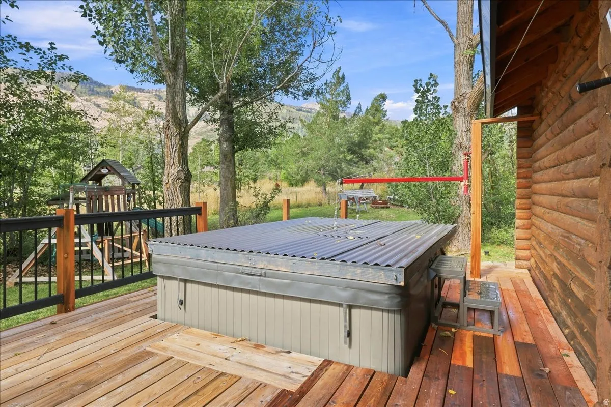 Wood plank deck featuring an integrated hot tub and natural wood log siding