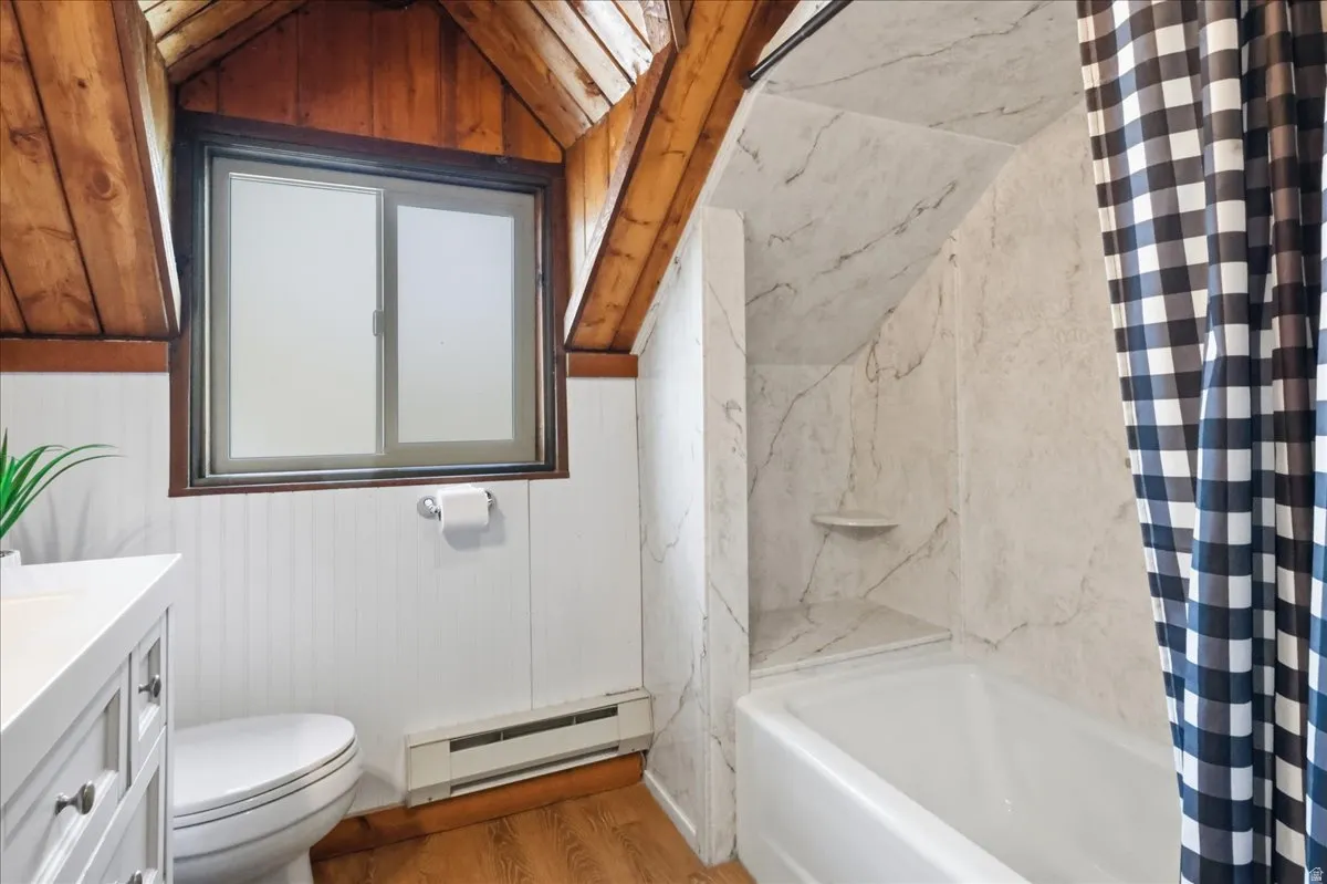Wood-finish flooring, white beadboard wall paneling, and a white vanity with cabinet storage