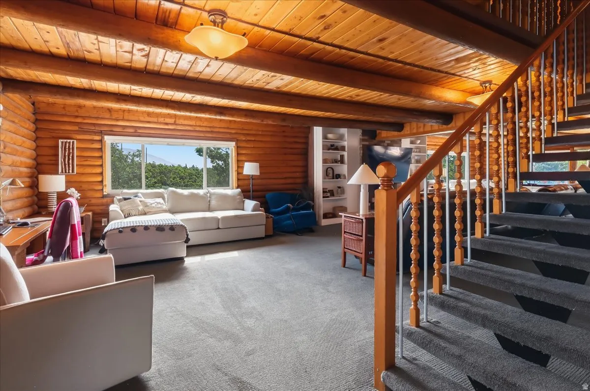 Log-style construction featuring exposed ceiling beams, a large picture window, and built-in shelving