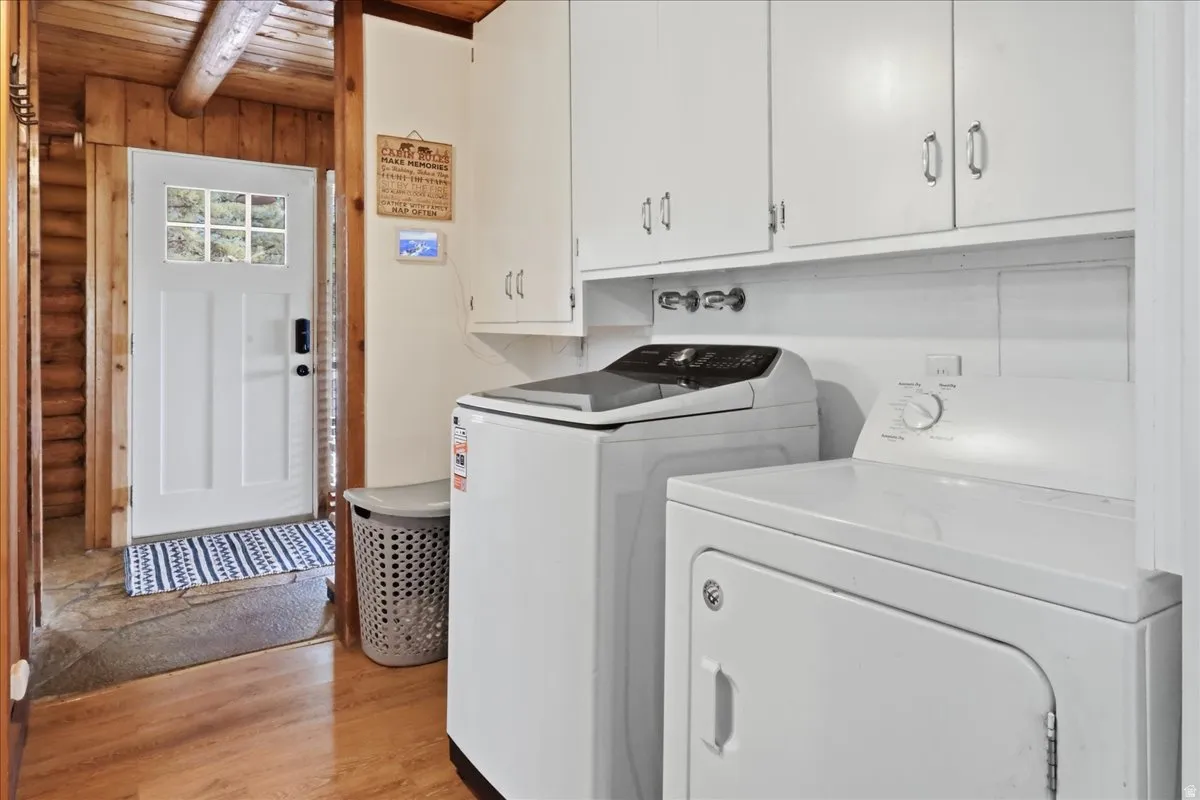 Laundry area featuring white cabinetry, wood-finish flooring, and a white paneled door with glass inserts