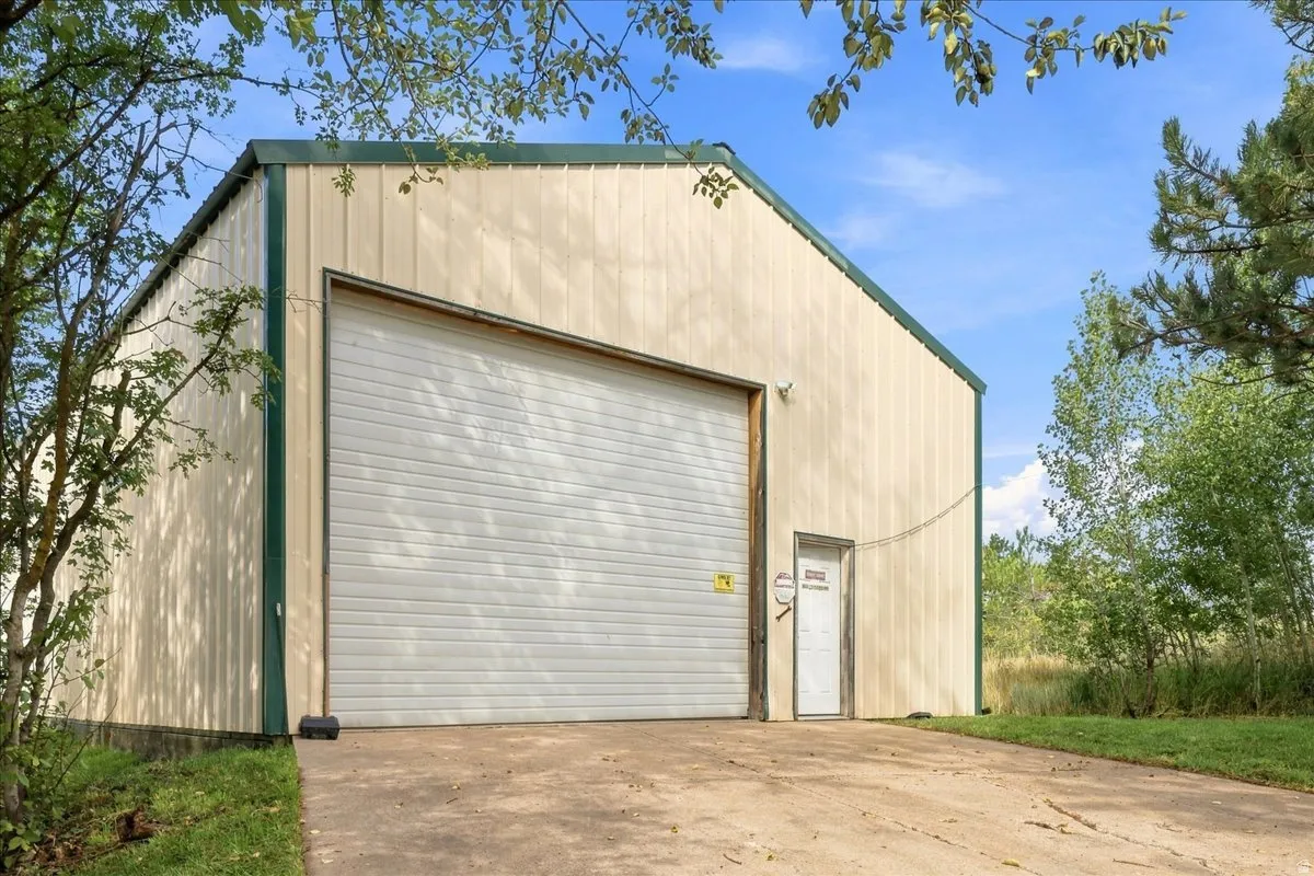 Metal-sided structure with a pitched metal roof, featuring a large roll-up door and an entry door