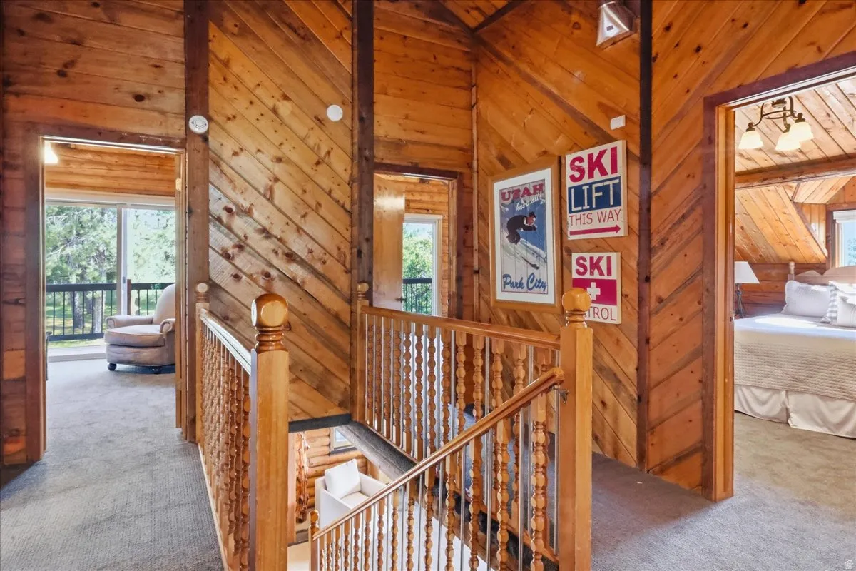Wood paneling throughout, wood-finish railing with turned newel post, and carpeted flooring