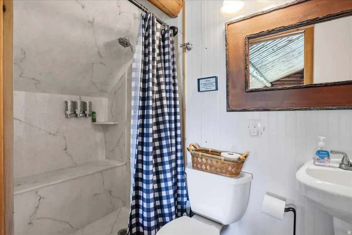 Shower with integrated bench and shelving, white vanity sink, and a wood-framed mirror