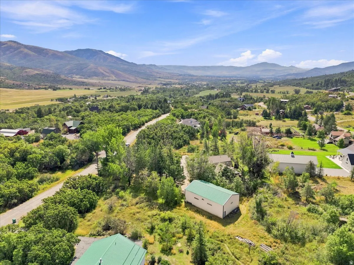 Expansive landscape with mountainous terrain, lush green valleys, and scattered residential properties