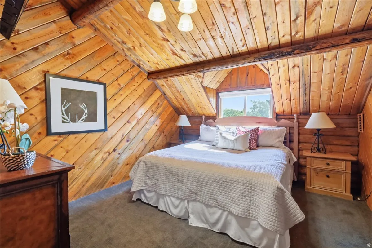 Wood-paneled sloped ceiling, exposed wood beams, and a window with a wood frame