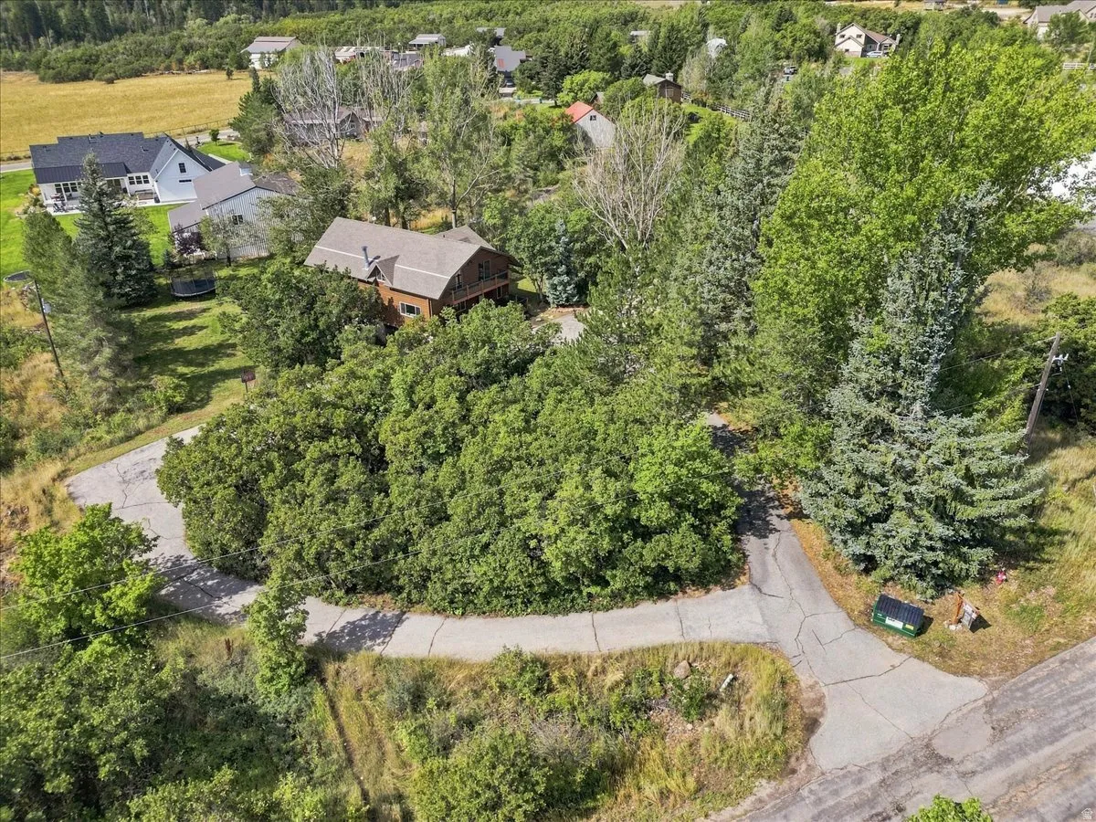 Wood-sided residence with a brown roof and a surrounding abundance of mature trees