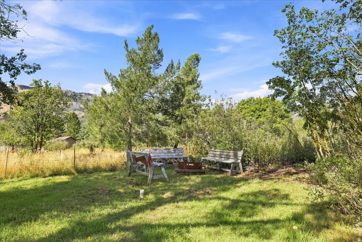 Grassed outdoor space featuring a fire pit area with rustic benches